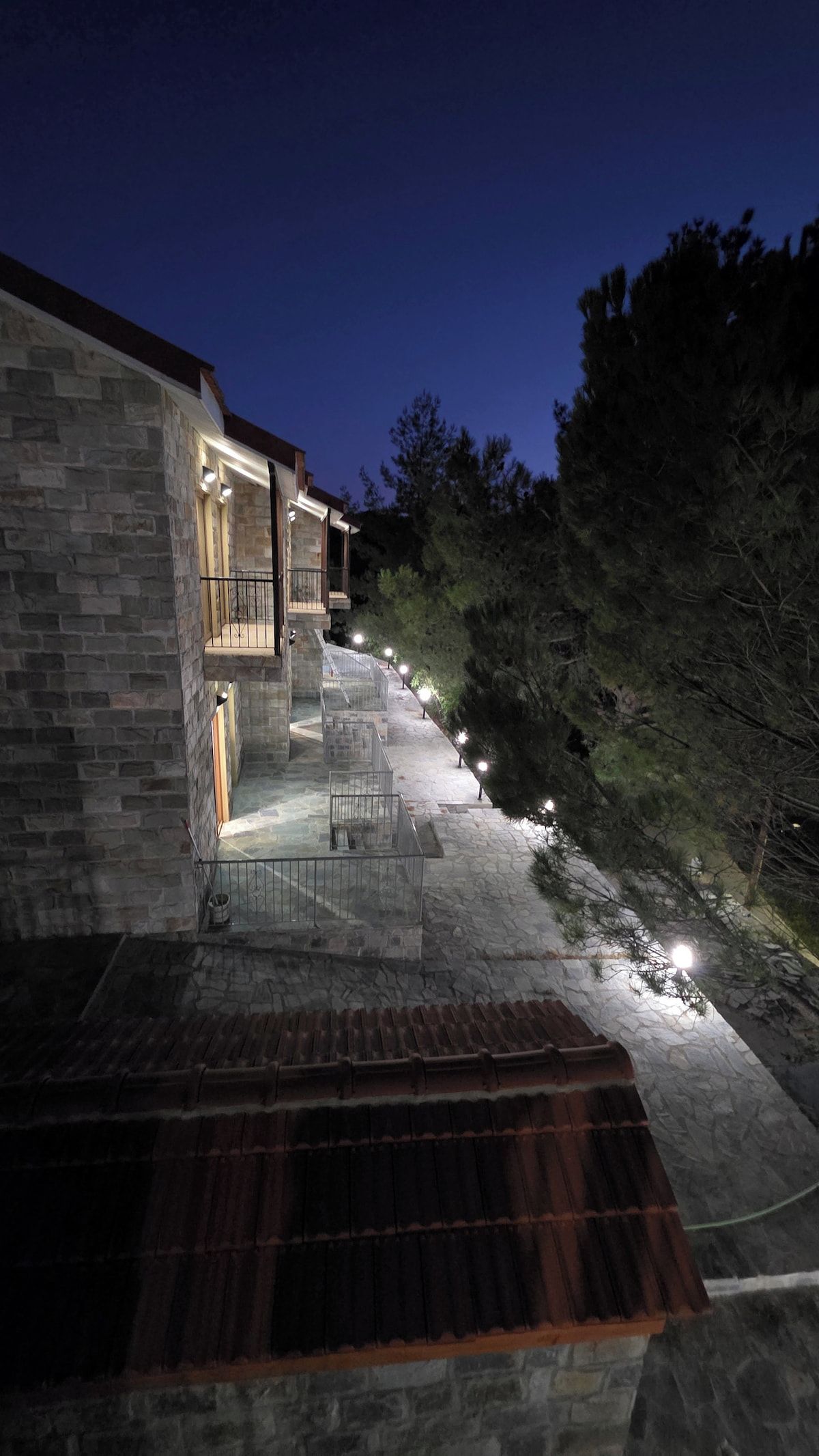 Un edificio de piedra con una escalera que conduce a un balcón, rodeado de árboles.