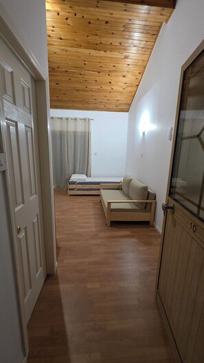 Una habitación con techo de madera, un sofá, una cama y una puerta.