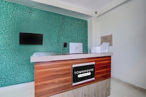 Uma receção com placa 'Townhouse', uma televisão de ecrã plano, telefone e impressora.