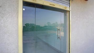 Una puerta de cristal con manija metálica, que da a una zona pavimentada.