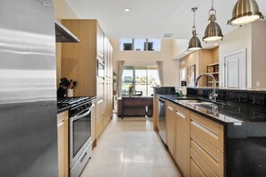 Een moderne keuken met roestvrijstalen apparatuur, houten keukenkastjes en hanglampen.