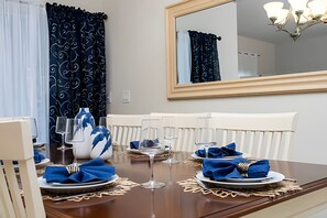 A dining table set with plates, glasses, and a vase. - 4BR w/ Pool + Mickey & Harry Potter Themes (Kissimmee)