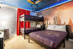 Ein Schlafraum mit Etagenbetten, einer Sternenhimmel-Decke, Wandgemälde mit Stadtansicht und einem roten Vorhang.