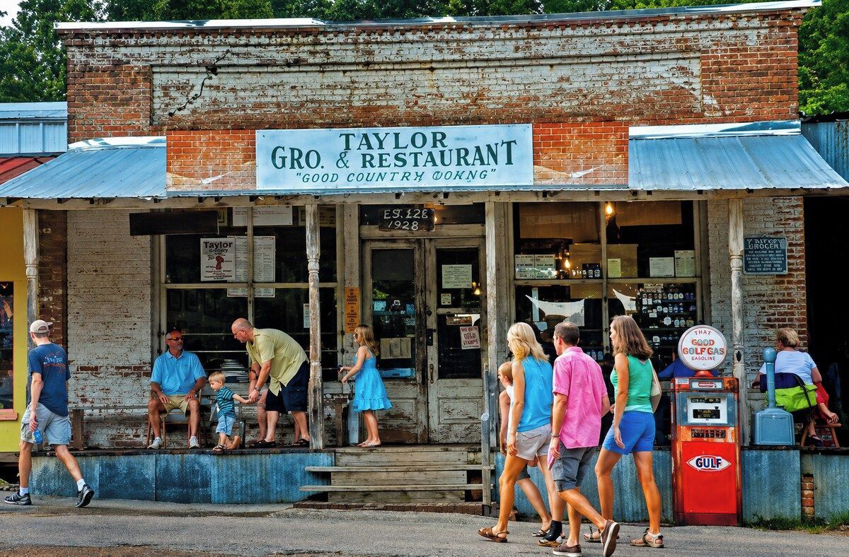 A vintage building with a sign reading 'Taylor Gro. & Restaurant' and a vintage gas pump.