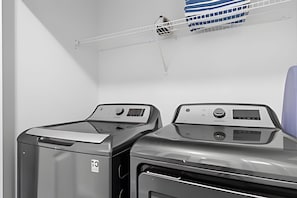 A laundry room with two front-loading washing machines and a drying rack above. - Disney 4BR w/ Pool + Themed Rooms in Storey Lake (Kissimmee)