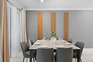 Comedor moderno con una mesa rectangular para seis comensales, sillas tapizadas en gris y una pared de acento gris con listones de madera verticales.