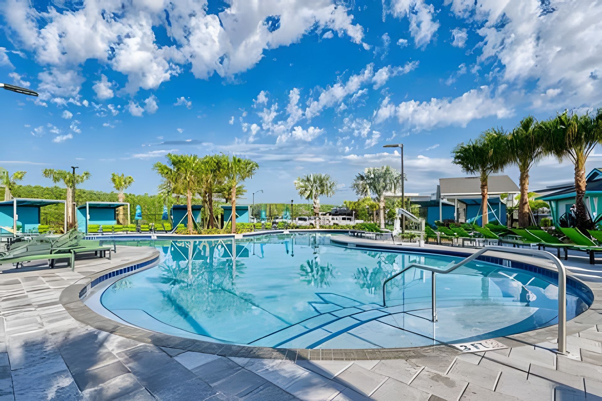 A circular pool with a clear blue sky and scattered clouds in the background.