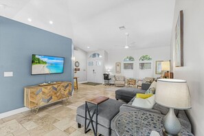 A spacious living room with a television, seating area, and a dining space. - Pineapple Paradise Retreat Private Pool and Spa (Bonita Springs)
