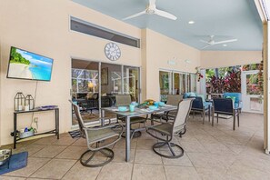 A spacious patio area with a dining table, chairs, and a ceiling fan. - Pineapple Paradise Retreat Private Pool and Spa (Bonita Springs)