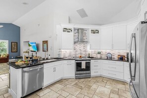 Een moderne keuken met witte kasten, een roestvrijstalen koelkast en een betegelde achterwand.
