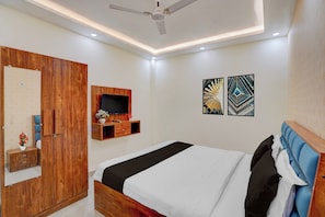 A modern bedroom with a bed, wooden wardrobe, TV, and artwork. - Super OYO Hotel O Rakabganj Crossway (Faizabad)