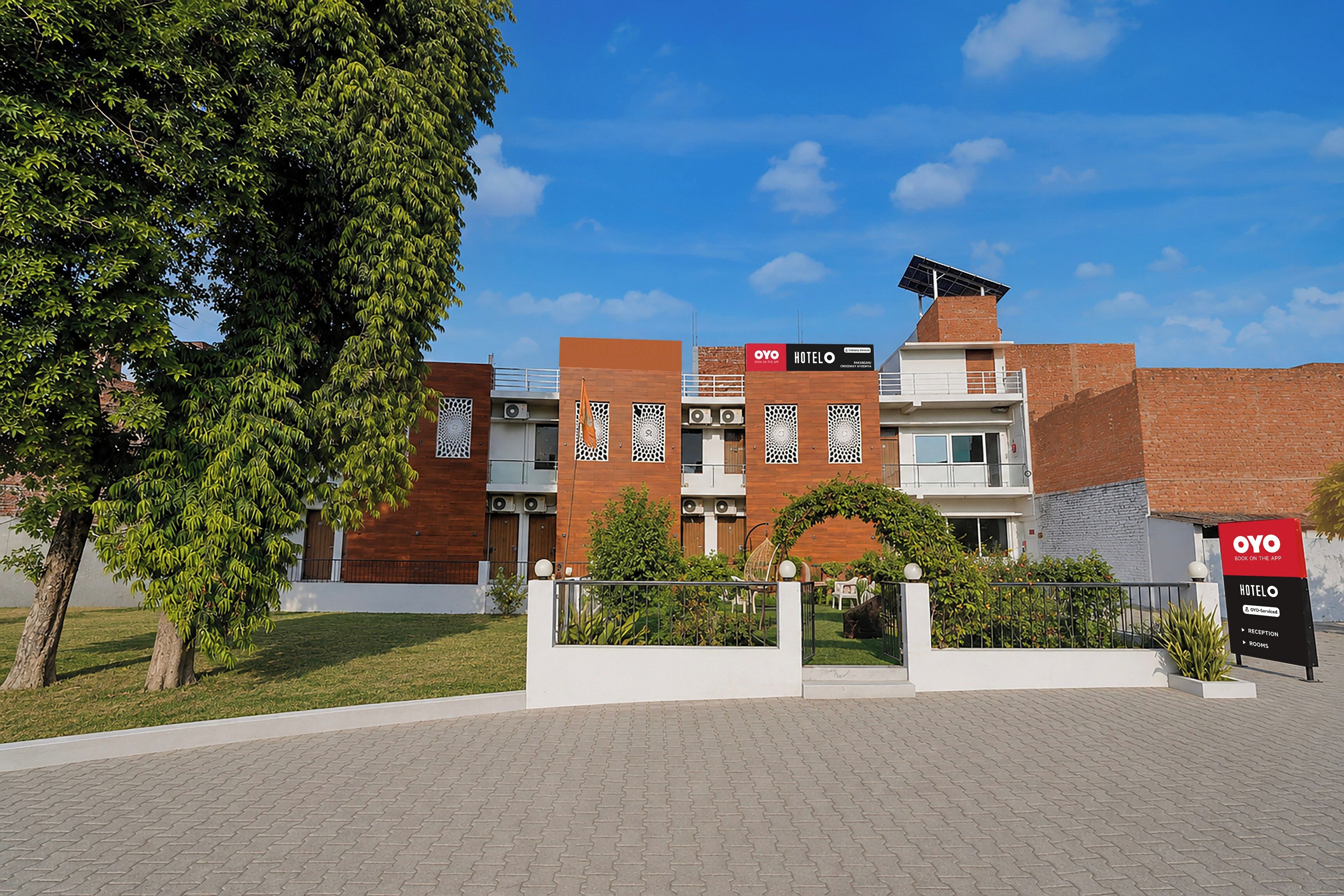Hotel amb disseny modern, façana de maó, panell solar a la teulada i zona de jardí paisatjista.