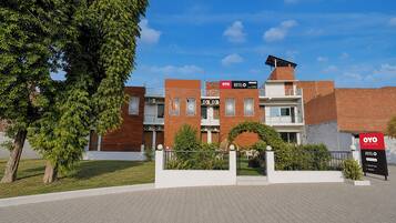 Hotel amb disseny modern, façana de maó, panell solar a la teulada i zona de jardí paisatjista.