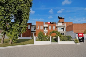 A hotel with a modern design, featuring a brick facade, a rooftop solar panel, and a landscaped garden area. - Super OYO Hotel O Rakabganj Crossway (Faizabad)