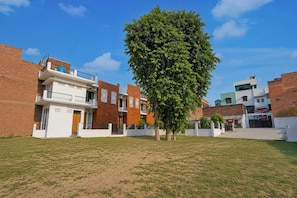 Una zona residencial con casas modernas, un árbol grande y un cielo azul despejado.