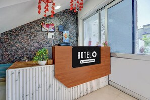 A hotel reception desk with a 'HOTELO' sign, a plant, and a window with a view of the outside. - Super OYO Hotel O Rakabganj Crossway (Faizabad)