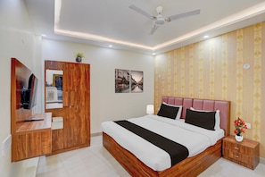 A hotel room with a bed, bedside table, wardrobe, and a ceiling fan.