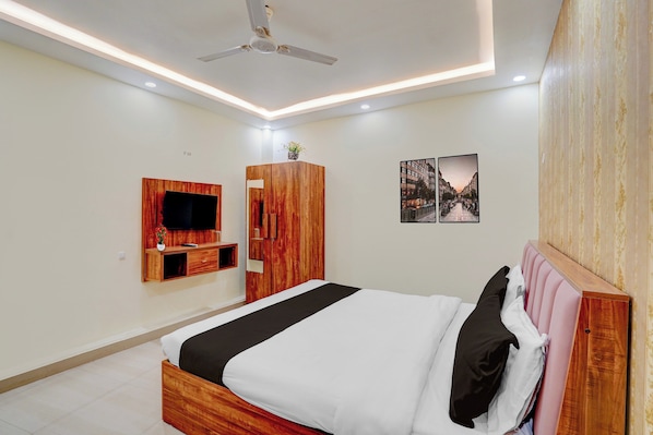 A modern bedroom with a bed, a TV mounted on the wall, a ceiling fan, and two framed pictures on the wall. - Super OYO Hotel O Rakabganj Crossway (Faizabad)