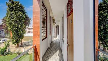 Passadís amb sòl estampat, una porta de fusta i vista a arbres i edificis.