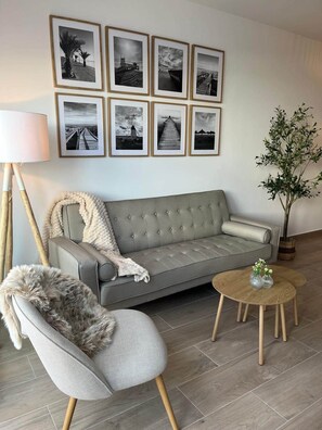 A living room with a grey sofa, a chair with a fur throw, a round coffee table with vases, and a floor lamp. - Molino Beach House - San Pedro del Pinatar (San Pedro del Pinatar)