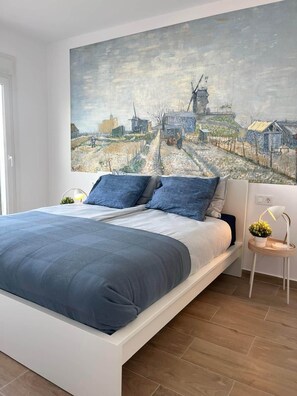 Ein Schlafzimmer mit einem großen Bett, einem Nachttisch, einer Lampe und einem Bild an der Wand.