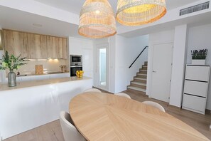 A modern kitchen with white cabinetry, a central island, and a dining area with a wooden table and chairs. - Molino Beach House - San Pedro del Pinatar (San Pedro del Pinatar)