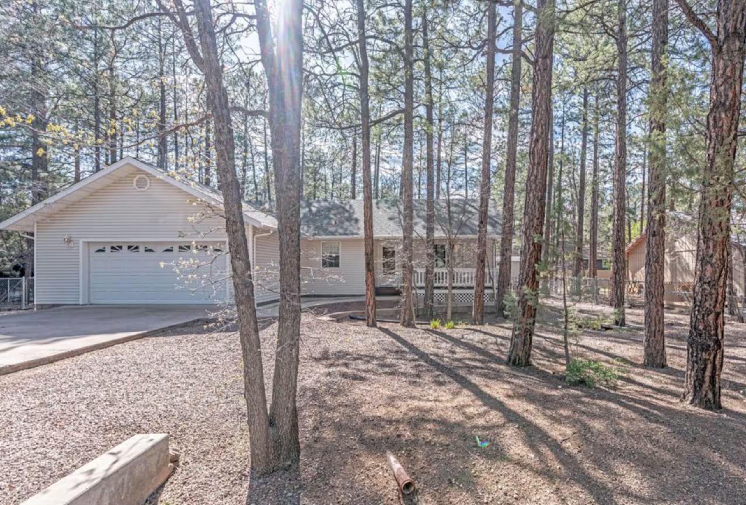 A single-story house with a garage, surrounded by a forested area.