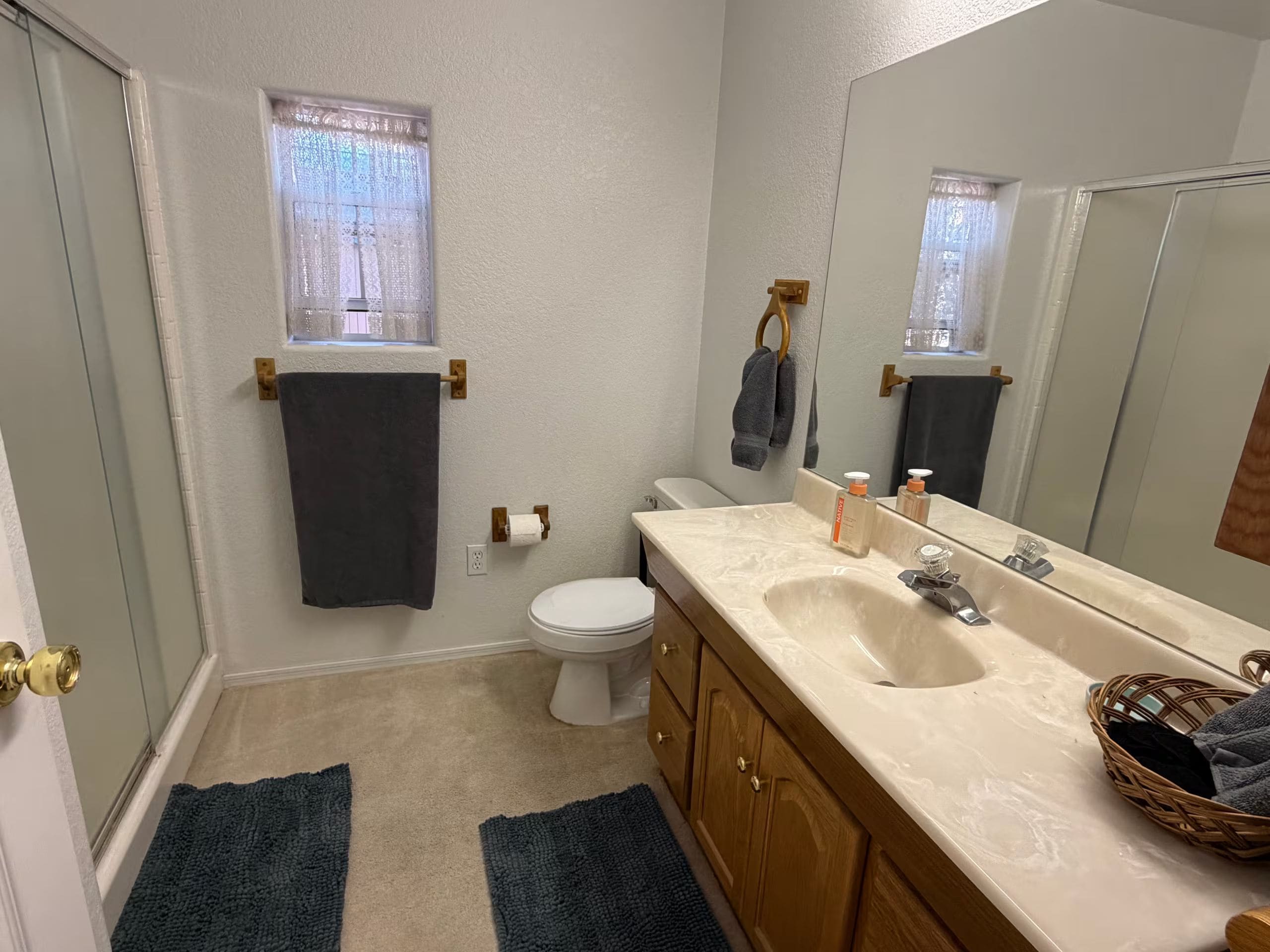 A bathroom with a toilet, sink, mirror, and towel rack.