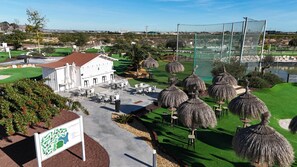 A golf course with a clubhouse, outdoor seating, and thatched umbrellas. - Residencial Exclusive - Santa Rosalia Lake Resort (Torre-Pacheco)