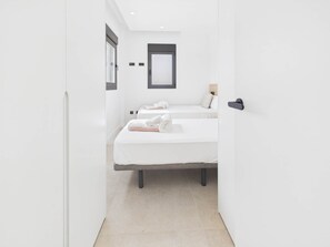 Habitació d'hotel moderna amb dos llits, una finestra gran i una porta.