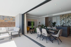 A modern living room with a dining area, a sofa, a coffee table, and a TV mounted on the wall. - Villa de los Suenos - Santa Rosalia Lake Resort (Torre-Pacheco)