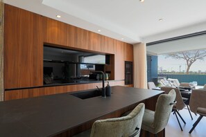 A modern kitchen with a dark countertop, wooden cabinets, and a built-in oven. - Villa de los Suenos - Santa Rosalia Lake Resort (Torre-Pacheco)