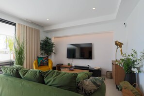 A modern living room with a green sofa, a yellow armchair, a flat-screen TV, and a decorative bird sculpture. - Villa de los Suenos - Santa Rosalia Lake Resort (Torre-Pacheco)