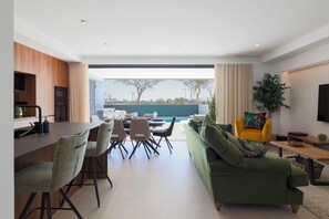 Un salon moderne comprenant un coin repas, un canapé, un téléviseur et une vue sur l’extérieur.