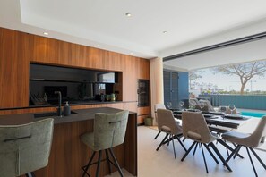 A modern kitchen with a built-in oven and a dining area with a pool view. - Villa de los Suenos - Santa Rosalia Lake Resort (Torre-Pacheco)