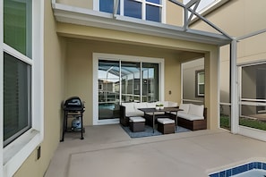 A patio area with a pool, a table with chairs, and a grill. - 5BR Villa w/ Pool & Game Room Near Disney (Davenport)