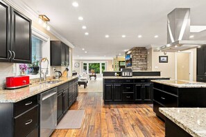 Una cocina moderna con armarios oscuros, encimeras de granito y una isla central.