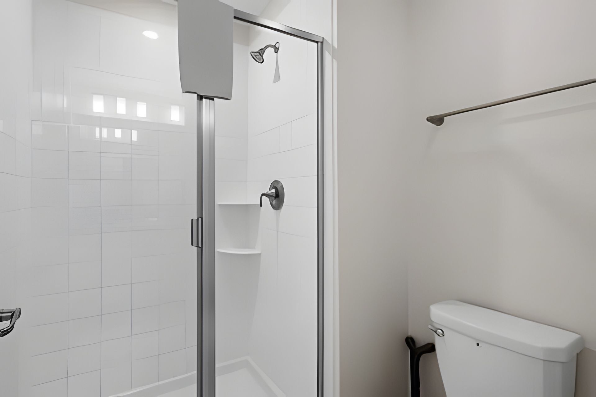 Een moderne badkamer met een douche met glazen wand, een toilet en een handdoekhouder.