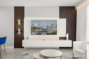 Una sala de estar moderna con un mueble blanco para el entretenimiento, una mesa redonda de centro y un sillón azul.