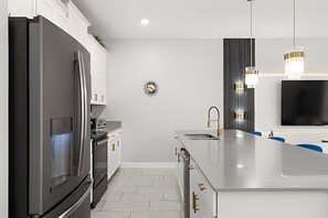 Una cocina moderna con un refrigerador de acero inoxidable, un horno empotrado y una isla grande con fregadero.
