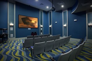 Un salón de conferencias con filas de sillas, un cuadro grande en la pared y una alfombra con un diseño ondulado.