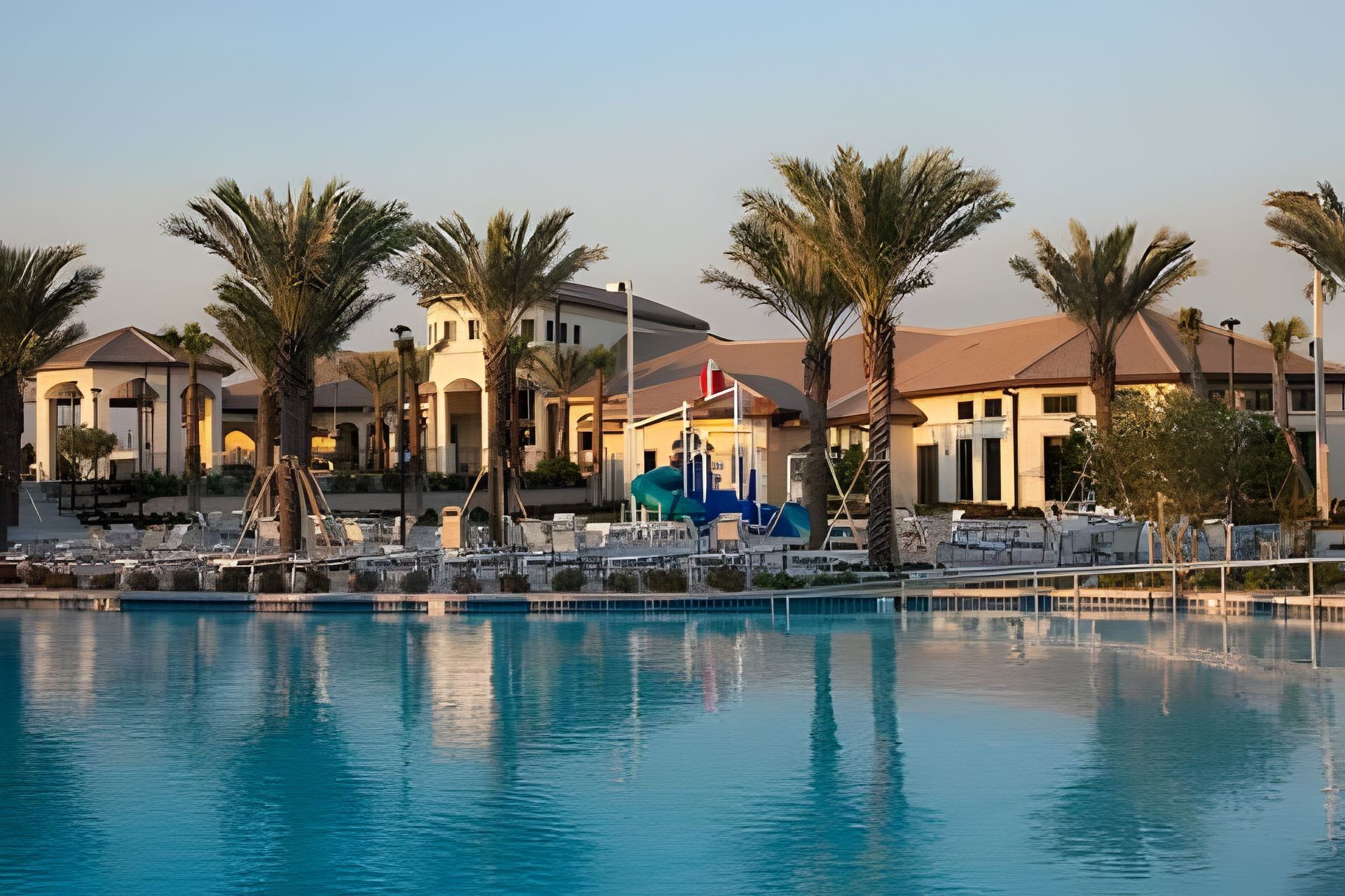 A resort with a swimming pool, palm trees, and a building with a dome roof.