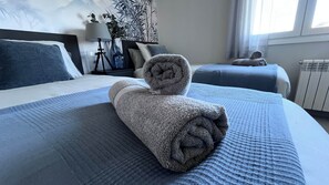 Un lit bien fait, avec une serviette enroulée, une table de chevet avec une lampe et une fenêtre avec des rideaux.