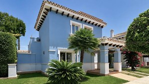 A two-story building with a blue facade, a tiled roof, and a covered entrance area. - Villa Oliver - Mar Menor Golf Resort (Torre-Pacheco)