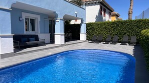 Une piscine dotée d’un espace détente intégré et de chaises longues.