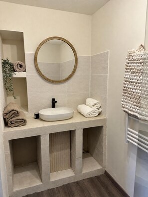 A bathroom with a round mirror, a sink, and a towel rack. - New Listing (Montauban)