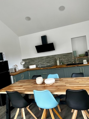 A modern kitchen with a wooden dining table, black and blue chairs, and a built-in stove. - New Listing (Montauban)