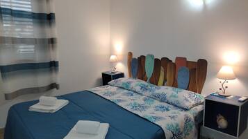 Une chambre d’hôtel avec un lit, deux tables de chevet, une lampe et un rideau.
