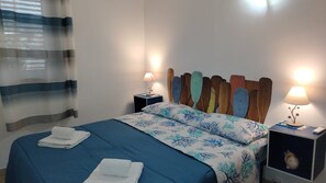 Une chambre d’hôtel avec un lit, deux tables de chevet, une lampe et un rideau.