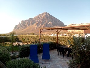 Une terrasse avec deux fauteuils bleus, une table et une structure en forme de pergola.